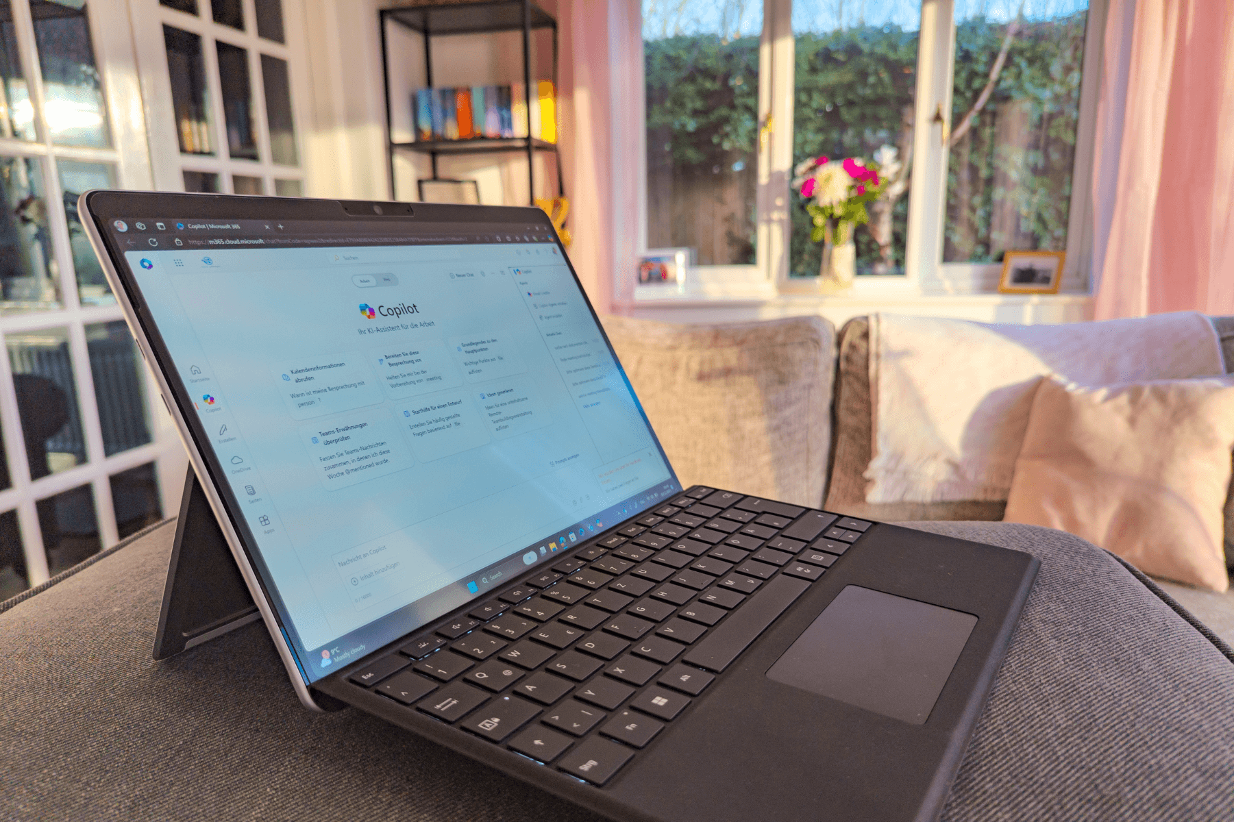 Ein Surface Pro 11 in einem Wohnzimmer. Der Display ist angeschalten und man sieht den Microsoft Copiloten.